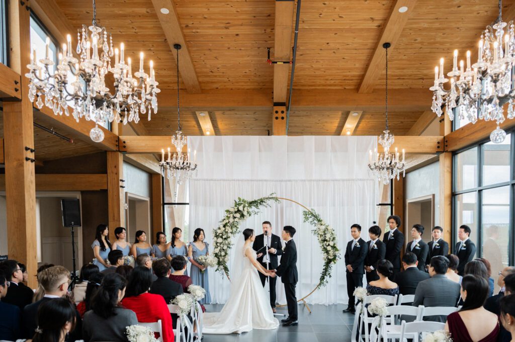 Lucy and Eric’s wedding day was nothing short of magical, celebrated at The View at Lincoln Park, Jersey City’s newest wedding venue. Managed by Landmark Venues, known for their collection of exceptional New Jersey wedding locations, this venue offers a unique blend of historic charm and contemporary design.
Nestled in the heart of Lincoln Park, The View boasts a picturesque setting with a waterfront backdrop and a stunning willow tree, ideal for dreamy wedding photos. The grounds are expansive, providing plenty of opportunities for couples to capture unforgettable moments. The venue’s modern architecture is a thoughtful adaptive reuse of the original Lincoln Lodge (Est. 1929), featuring its preserved stone façade, timber beams, and antique fixtures. The result is a space that feels both timeless and modern—perfect for any couple’s big day.
One of the standout features of The View is its three-level design, allowing couples to seamlessly host their ceremony, cocktail hour, and reception on separate floors. This layout ensures each part of the day has its own dedicated atmosphere. Add to that the convenience of onsite bridal and groom’s suites, and you have a one-stop wedding destination right in Jersey City!
On Lucy and Eric’s wedding day, the weather forecast threatened rain, but they were determined to have outdoor photos by the water and under the willow tree. With a little luck and perfect timing, the rain held off just long enough for us to capture those beautiful moments outside. Later, as the rain poured, no one seemed to mind—it was time to celebrate indoors!
Surrounded by their loving family and friends, Lucy and Eric danced, laughed, and created memories to last a lifetime. Their wedding was a perfect reflection of their love and joy, and I couldn’t be happier for them.
Congratulations, Lucy and Eric! Wishing you all the best in your new journey together.
Lucy and Eric The View at Lincoln Park Jersey City NJ Wedding photographed by MJ from Pearl Paper Studio. Pearl Paper Studio is here to capture real emotions, fun couples with non-traditional wedding stories, now we are booking small intimate backyard wedding, outdoor tent wedding, farm wedding, elopements, nyc elopements. We are currently booking 2025 and 2026 weddings in NJ, Manhattan, Hudson Valley NY, Brooklyn and Long Island.