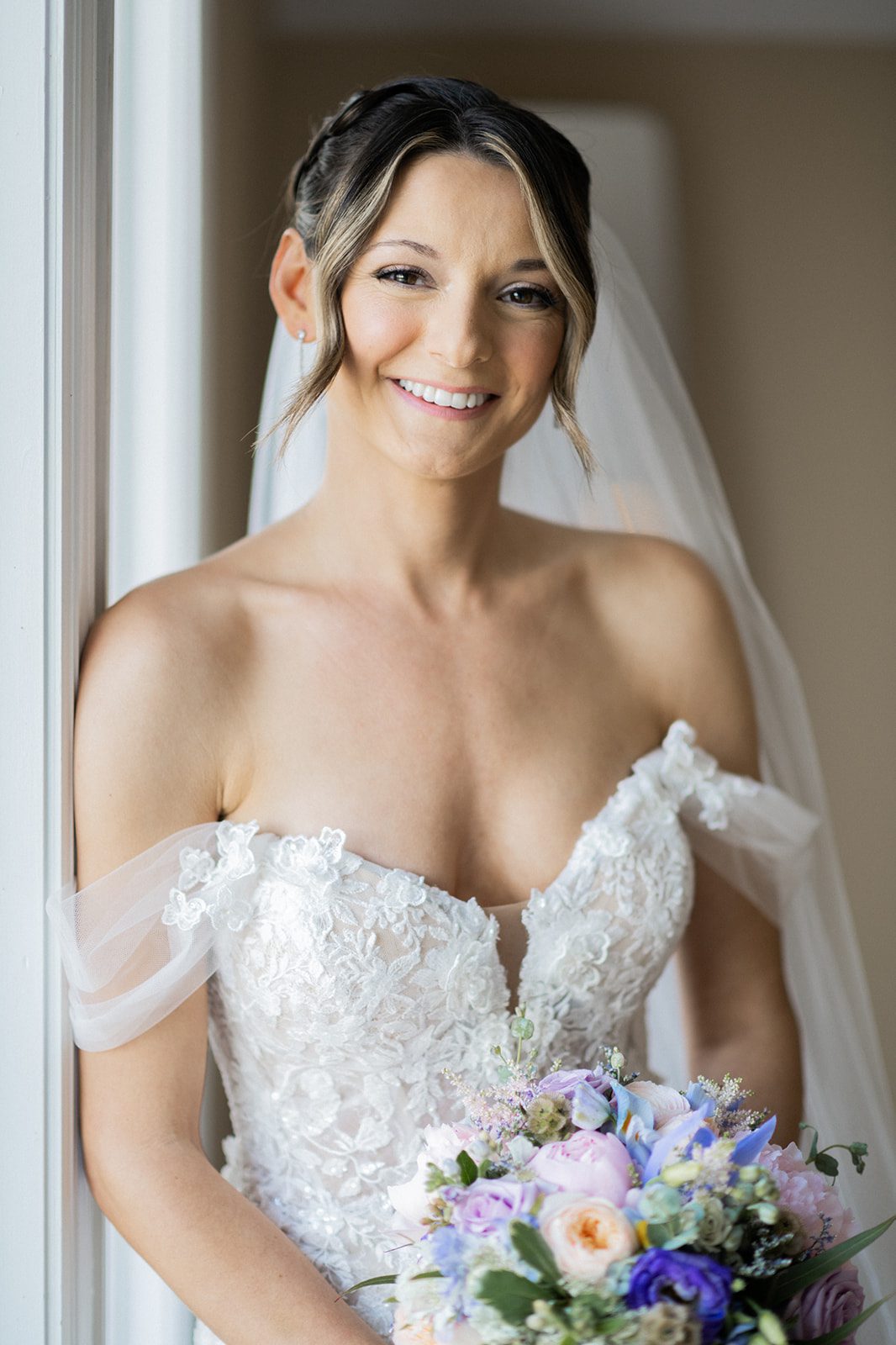 Bride smiling with her bouquet and veil in a window portrait at Rock Island Lake Club.
