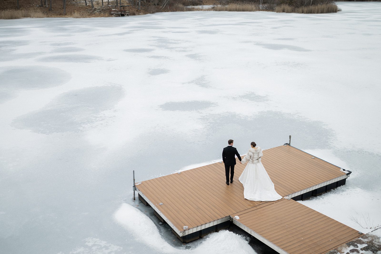 Couple standing on the dock over the frozen lake at Rock Island Lake Club.