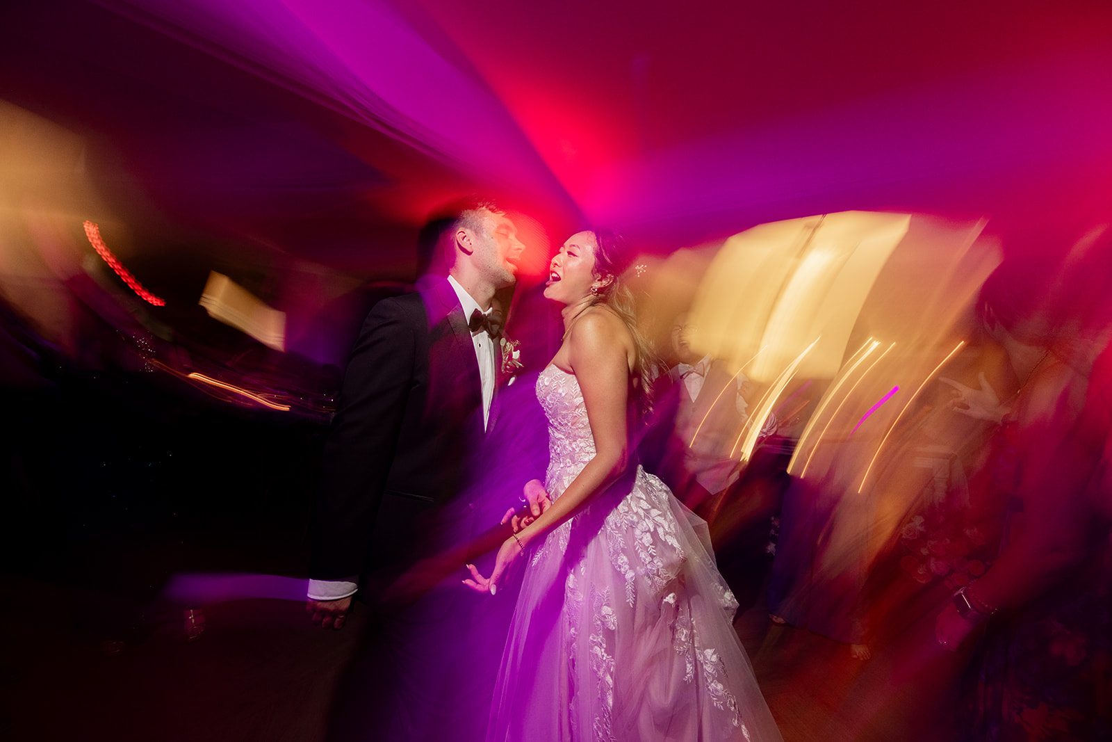 Allison and Kevyn dancing in a motion-blur portrait under purple and red lights.