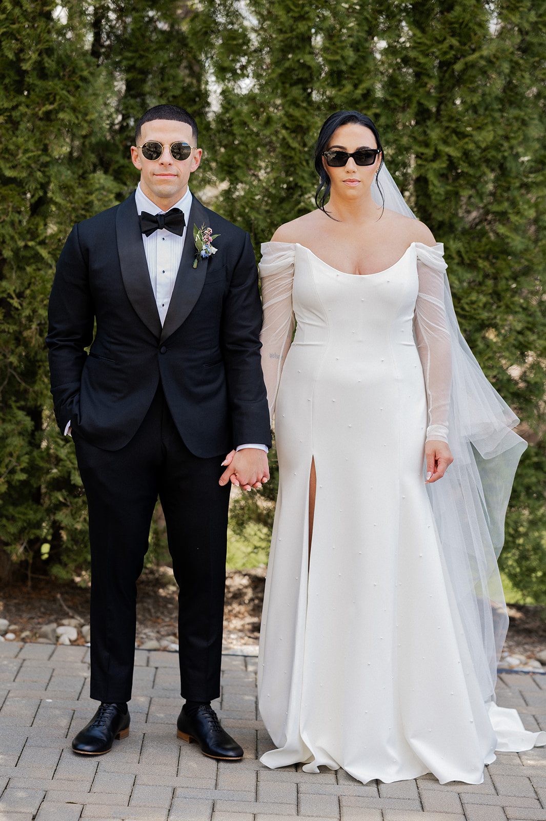 Ashley and Monte stand together in sunglasses for a playful couple portrait.