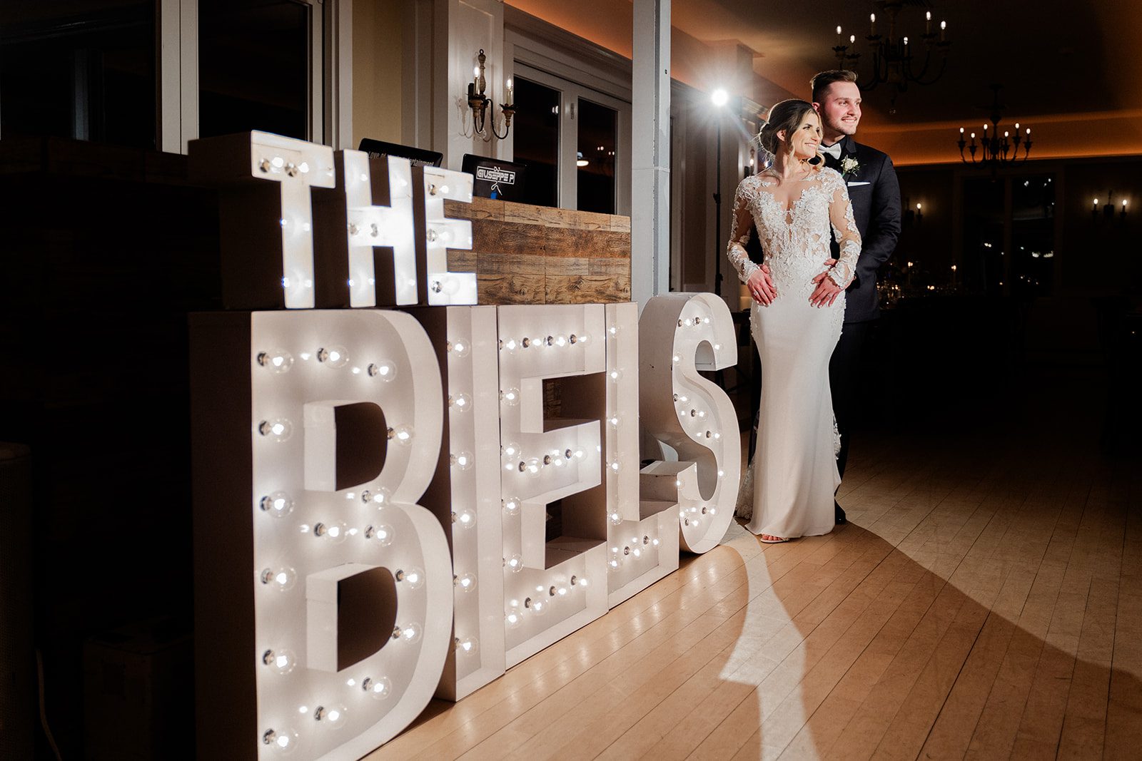 Elyse and Lucas pose beside the illuminated marquee letters spelling The Biels.