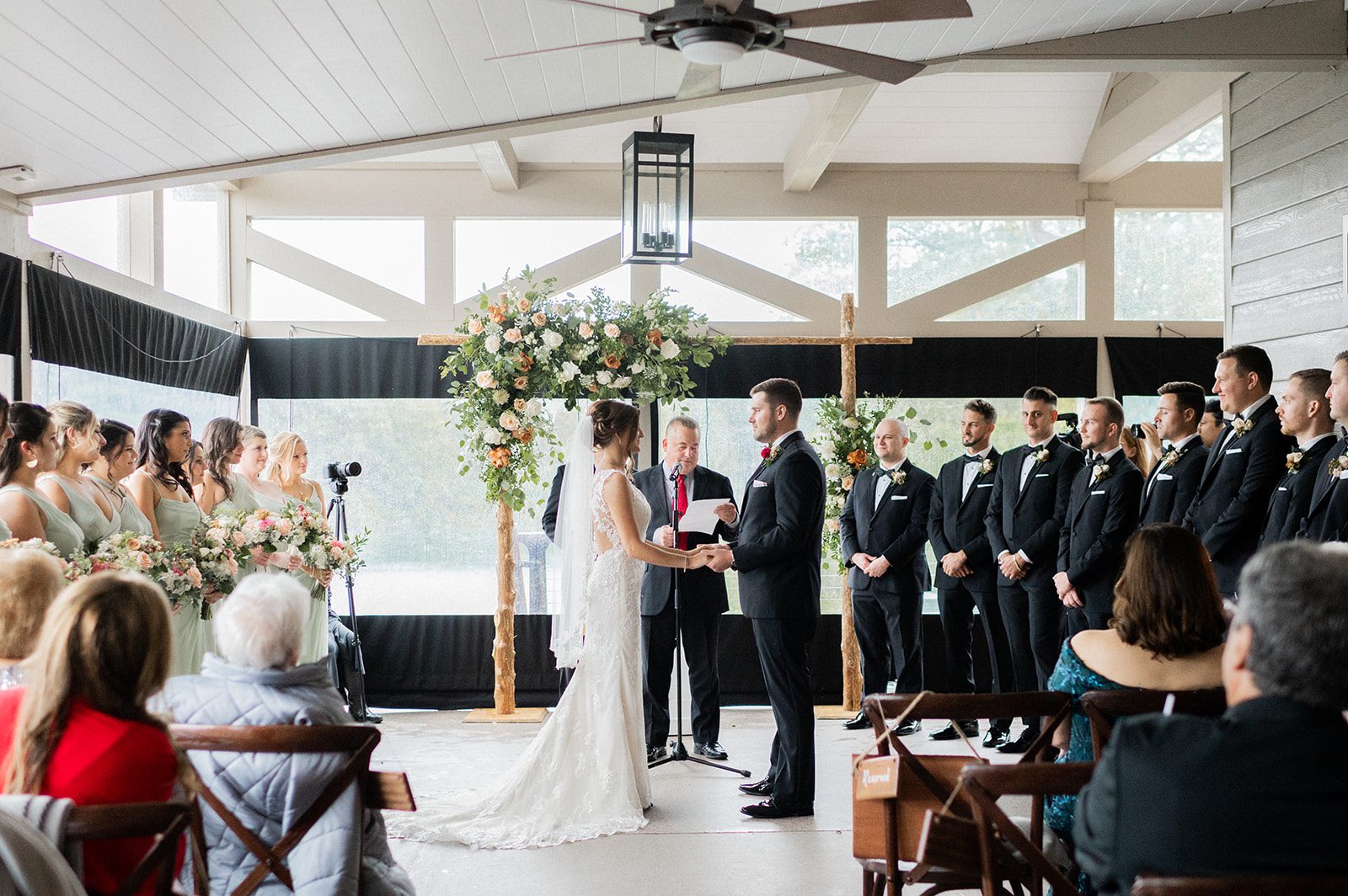 Brianne and Jack stand beneath the floral arbor during their lakefront ceremony.