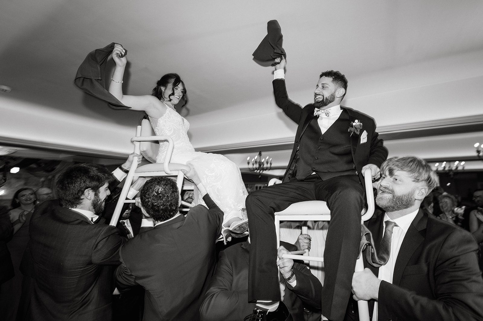 Madison and Ben lifted in chairs during the hora with guests gathered close.